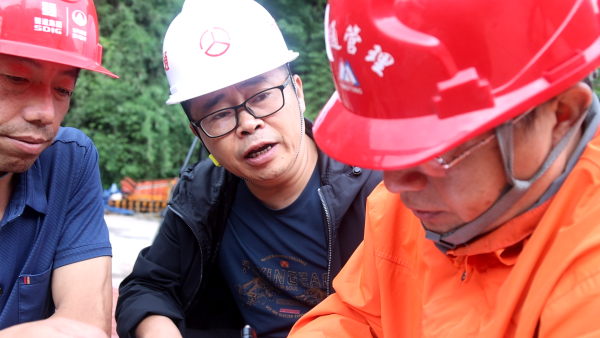 鄧慶（中）在項目現場討論施工要點。