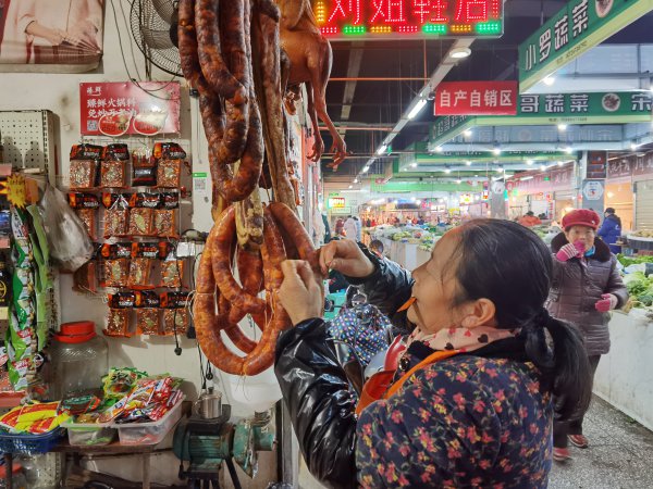 文安農貿市場內，商鋪老板正在整理香腸。